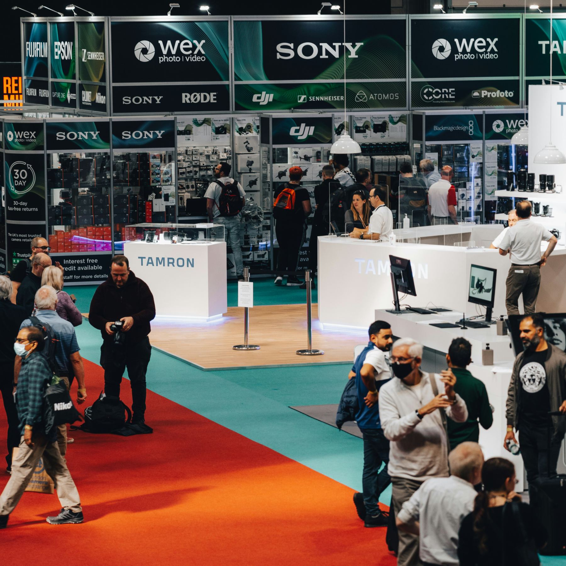 Visitors moving between branded exhibition stands on a busy expo floor.