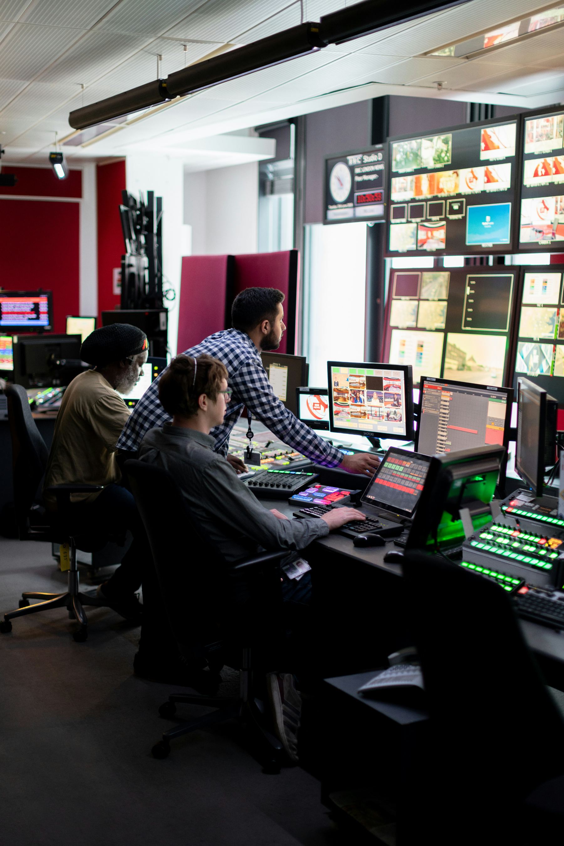 A vision-mixer monitor showing four camera feeds, colour bars and audio meters, with the studio set out of focus behind.